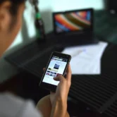 A person creating a listing brochure on a smartphone while standing in front of a property