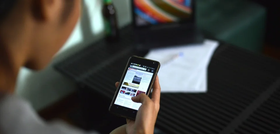 A person creating a listing brochure on a smartphone while standing in front of a property