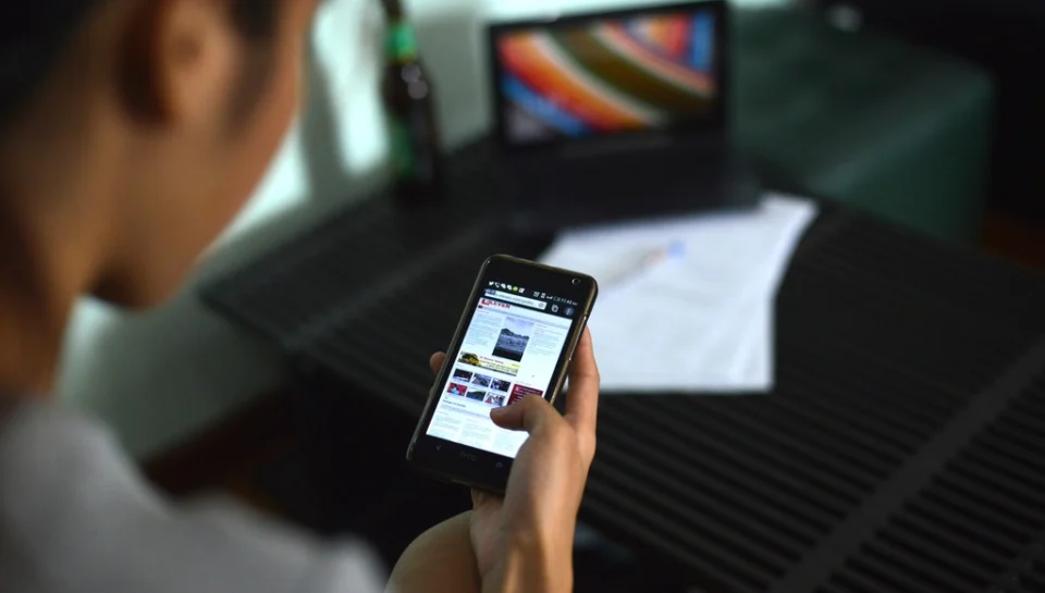 A person creating a listing brochure on a smartphone while standing in front of a property