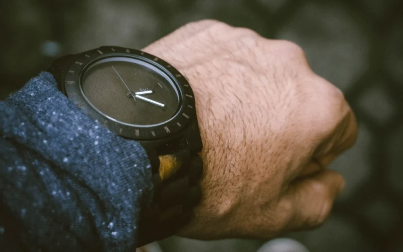 Luxury automatic watch photographed on a neutral background beside its box and warranty papers