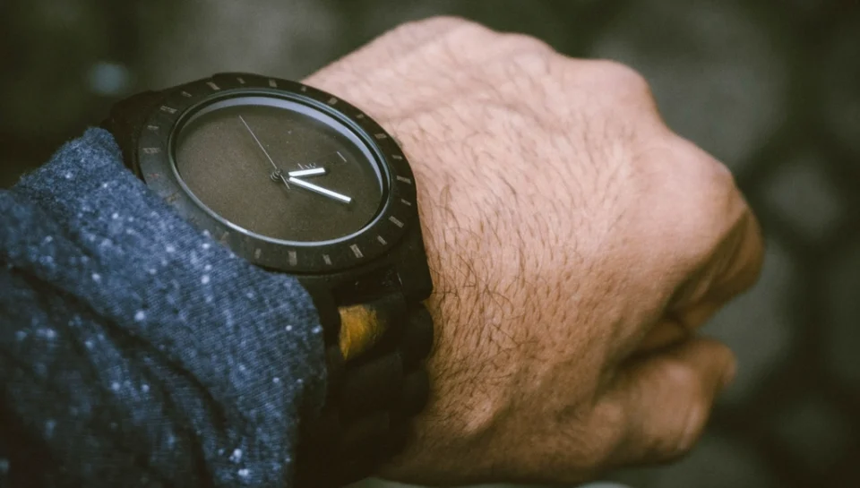 Luxury automatic watch photographed on a neutral background beside its box and warranty papers